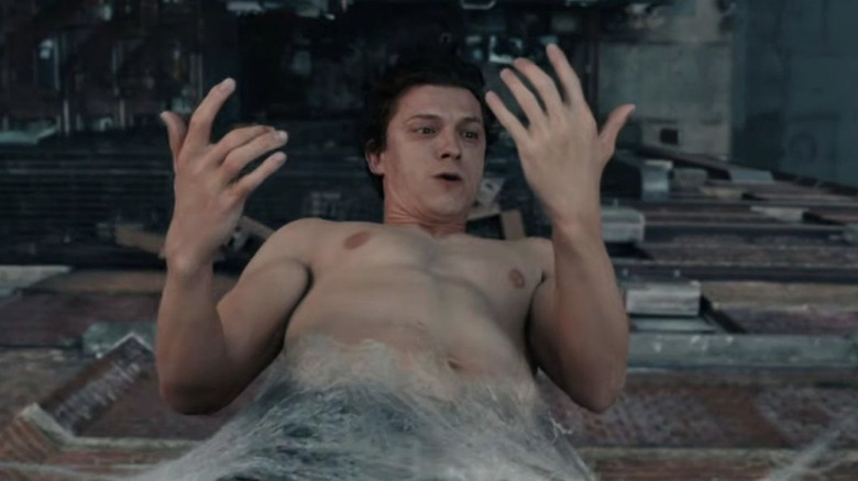 Tom Holland as Peter Parker hanging upside down in a web of silk in Spider-Man: Brand New Day