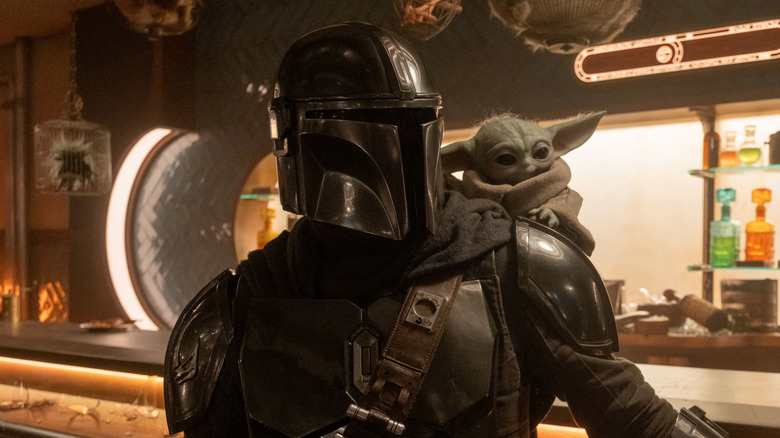 Grogu riding on Mando's back while he's standing at a bar in The Mandalorian and Grogu
