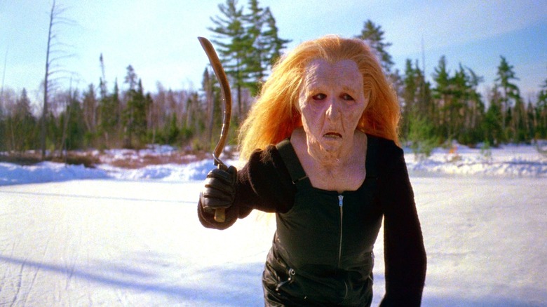 Jo-Anne Hannah as Patti O'Connor in Curtains, wearing an unsettling old hag mask as she crosses a frozen lake in broad daylight, wielding a sickle.