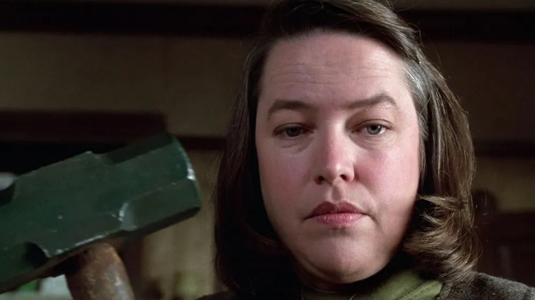 A close-up of Kathy Bates as Annie Wilkes in Misery, holding a sledgehammer and looking down just below the frame.