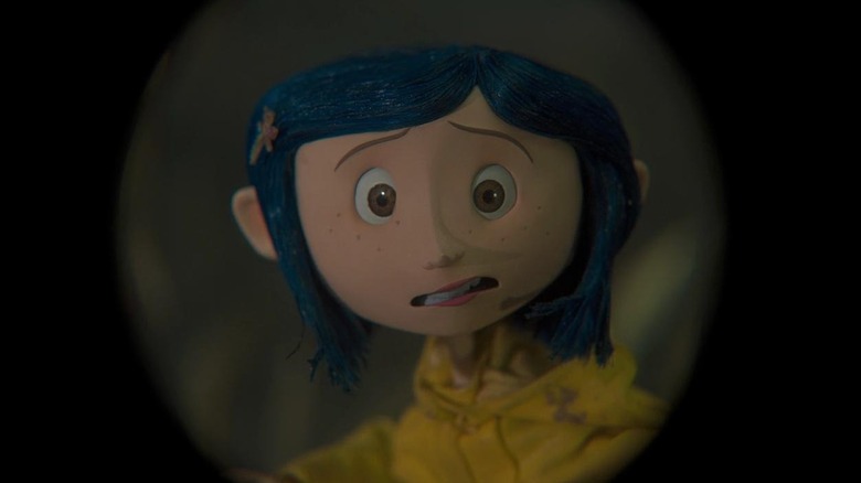 Coraline (Dakota Fanning) looking through a hole in Coraline