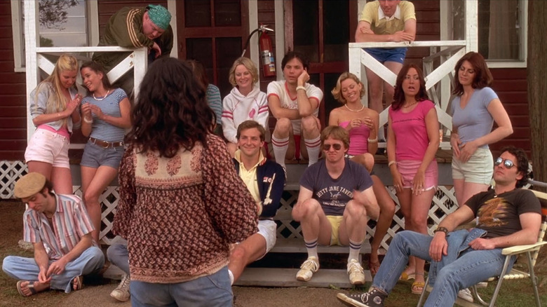 The ensemble cast of counselors of camp sit together on a porch in Wet Hot American Summer