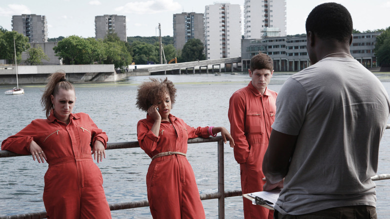 Three juvenile inmates talk someone in front of a lake in Misfits.