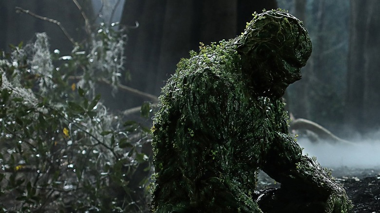 Derek Mears as Swamp Thing, sitting in a swamp in Swamp Thing.