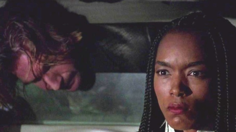 Ralph Fiennes as Lenny Nero peeking through the partition of a limousine while Angela Bassett as Lornette "Mace" Mason drives it in Strange Days