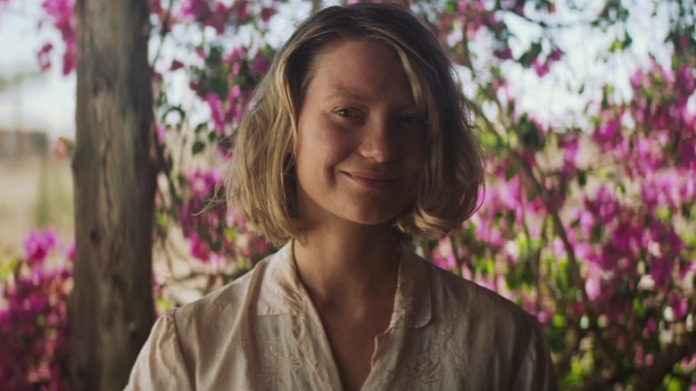 Robyn (Mia Wasikowska) smiling in front of flowers in Tracks