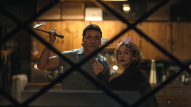 Oscar Isaac as Josh Martín holding up a golf club and grabbing Carey Mulligan as Lindsay Crane-Martín as they're caught in the middle of an argument in Beef