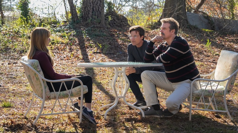 Carol sits at a lawn table opposite Clark and Floyd in her backyard on DTF St. Louis
