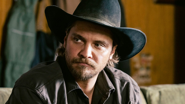 Luke Grimes' Kayce Dutton looks off to his right as he sits in a cabin in Marshals