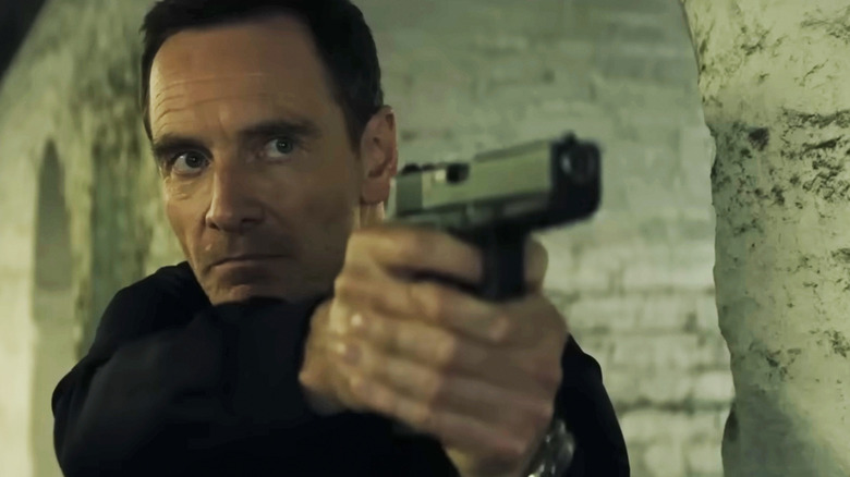 Michael Fassbender's Martian aims a pistol in The Agency