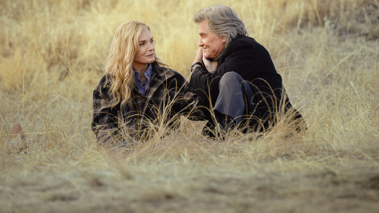 Stacey (Michelle Pfeiffer) and Preston (Kurt Russell) sitting in the grass on "The Madison."