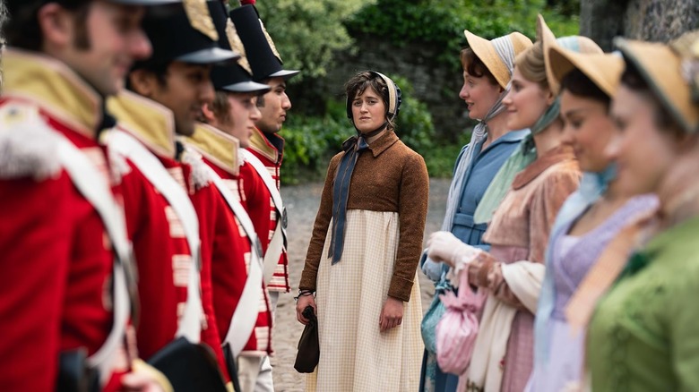 Ella Bruccoleri as Mary Bennet flanked by men in uniforms and women in hats and dresses in The Other Bennet Sister