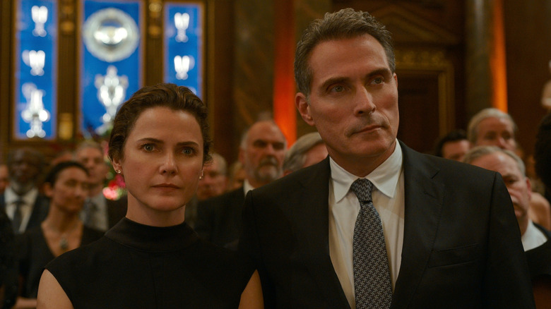 Kate Wyler (Keri Russell) and Hal Wyler (Rufus Sewell) watch someone speak in The Diplomat