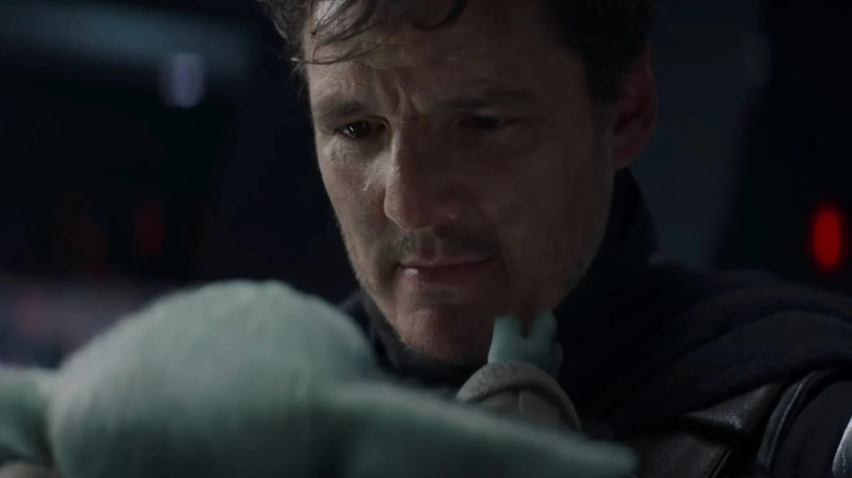 Pedro Pascal as Din Djarin looking at Grogu in The Mandalorian
