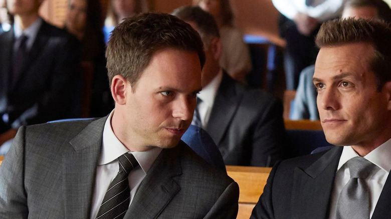 Patrick J. Adams and Gabriel Macht as Mike Ross and Harvey Specter sitting together in court on Suits