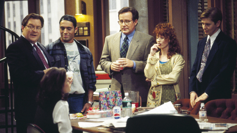 Joe Rogan as Joe Garrelli, Stephen Root as Jimmy James, Phil Hartman as Bill McNeal, Vicki Lewis as Beth,  and Dave Foley as Dave talk to Maura Tierney as Lisa at a desk in Newsradio