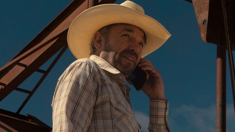 Tommy Norris wears a cowboy hat and talks on the phone in Landman