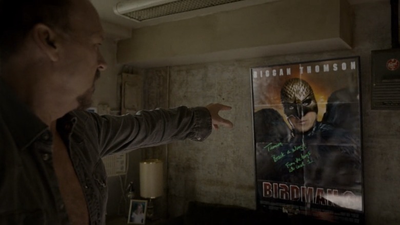 Riggan pointing at a Birdman movie poster