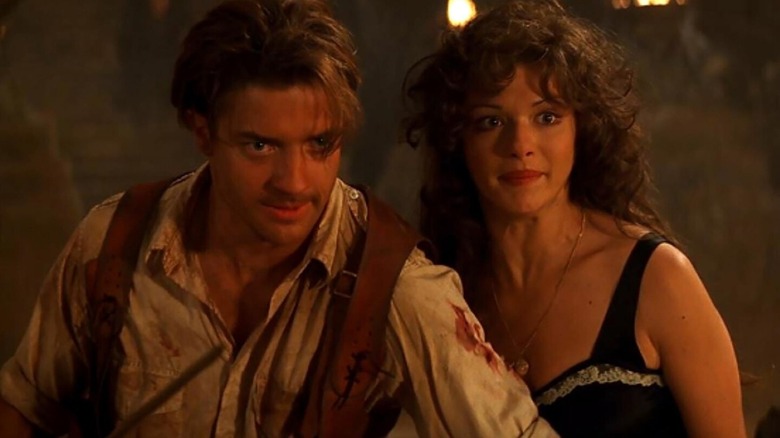 Brendan Fraser as Rick O'Connell and Rachel Weisz as Evelyn Carnahan standing in a tomb lit by torches in The Mummy