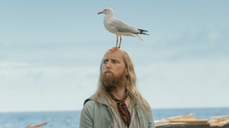 Ewen Bremner as Buttons, standing with a bird on his head in Our Flag Means Death