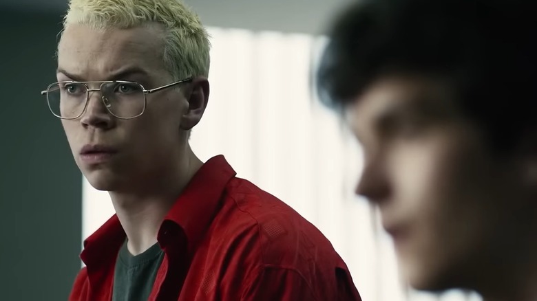 Will Poulter's Colin looks incredulously at someone (who Fionn Whitehead's Stefan, blurry in the foreground, also speaks to) in Black Mirror: Bandersnatch