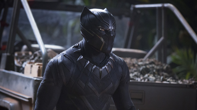 Chadwick Boseman as T'Challa standing by a truck in Black Panther