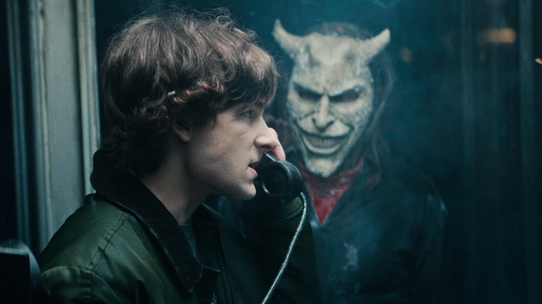 The Grabber stares at Finney from outside a payphone booth in The Black Phone 2
