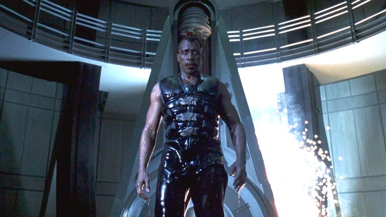 Wesley Snipes as Blade dripping with liquid in front of a big pylon with sparks in Blade II