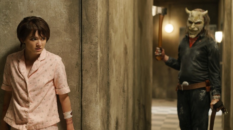 Madeleine McGraw as Gwen hiding behind a wall from Ethan Hawke as The Grabber in Black Phone 2