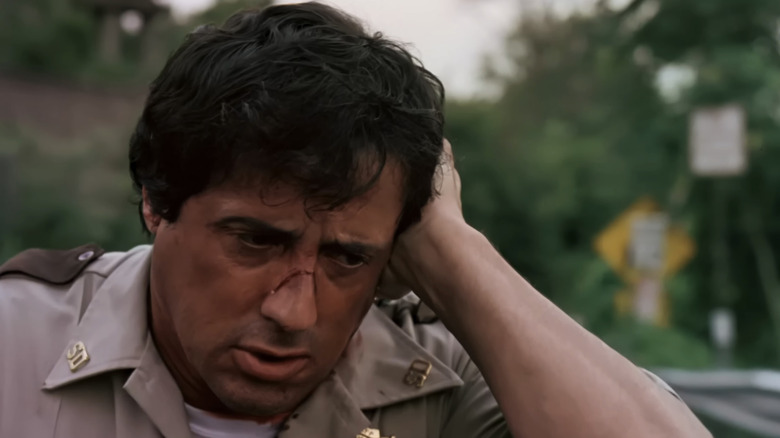 Sylvester Stallone's Sheriff Freddy Heflin holds his head as he stands outside in Cop Land