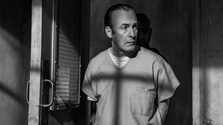 Saul Godman enters the prison visit room while wearing a prison suit in the end in black and white 