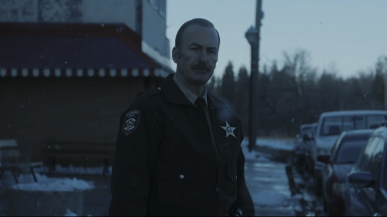 Bob Odenkirk's Sheriff Ulysses stands in a snowy street in Normal