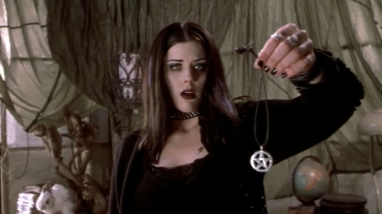 Kim Director as Kim holding up a necklace with a look of fear on her face in Book of Shadows: Blair Witch 2