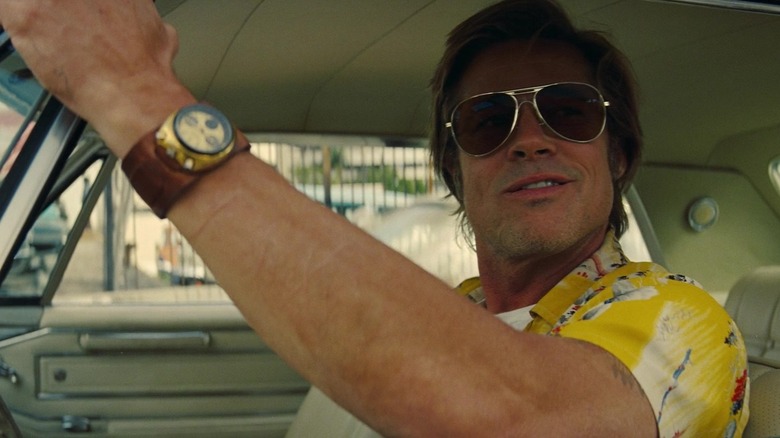 Brad Pitt as Cliff Booth ginning while looking out the window of his car in Once Upon a Time in Hollywood