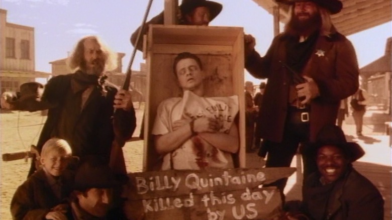 Some Western gunslingers posing around a corpse in an episode of Tales from the Crypt