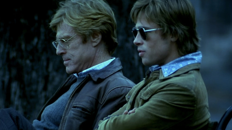 Tom Bishop de Brad Pitt is sitting on a bench next to the Nathan Muir of Robert Redford in Spy Game