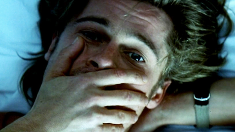 Brad Pitt's Tom Bishop puts his hand over his mouth while laying in bed in Spy Game