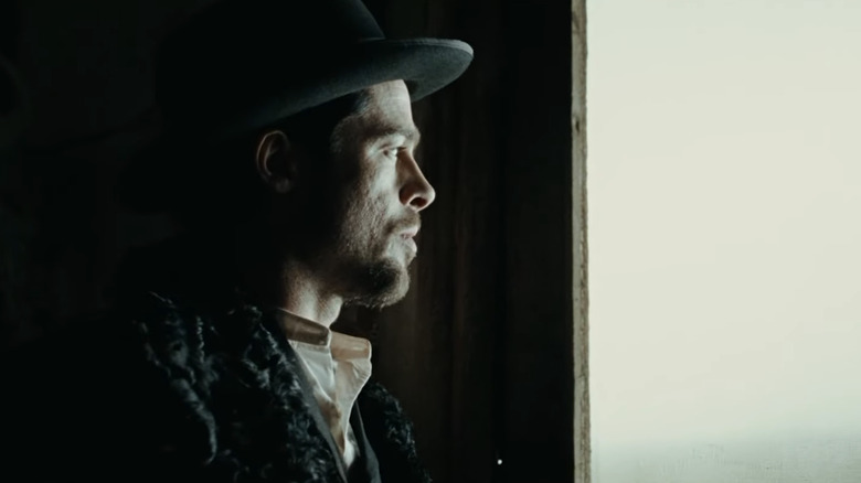 Jesse James van Brad Pitt kijkt uit een raam in The Assassination of Jesse James van de lafaard Robert Ford