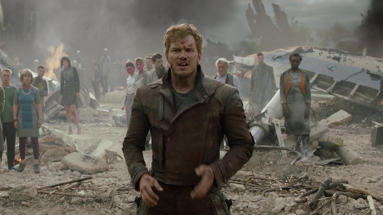Chris Pratt's Starlord stands in a dusty setting with a crowd behind him in Guardians of the Galaxy.jpg