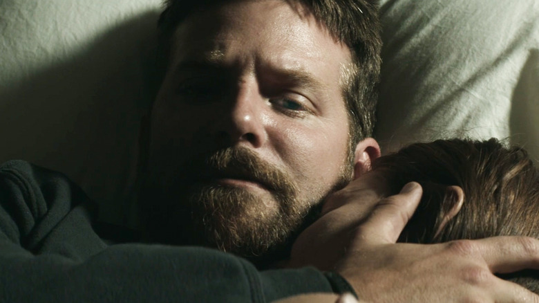 Bradley Cooper's Chris Kyle lays in bed holding his wife in American Sniper
