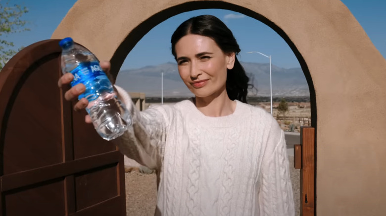 A woman offers a bottle of water in Pluribus