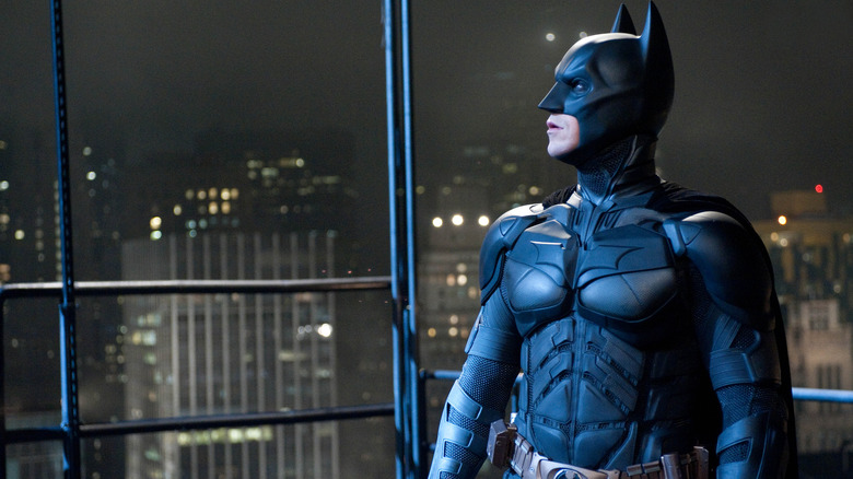 Christian Bale as Batman in costume looking up towards the sky in The Dark Knight Rises