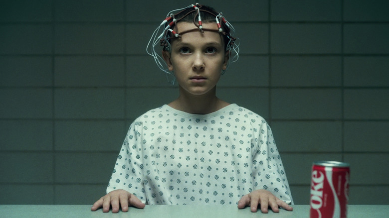 Eleven with electrodes on her head trying to crush a can with her mind at Hawkins Lab in Stranger Things