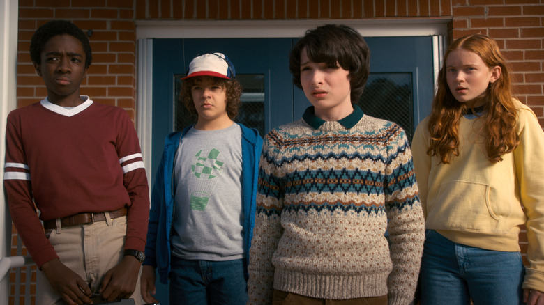 Mike, Dustin, Lucas, and Max standing on a porch in Stranger Things