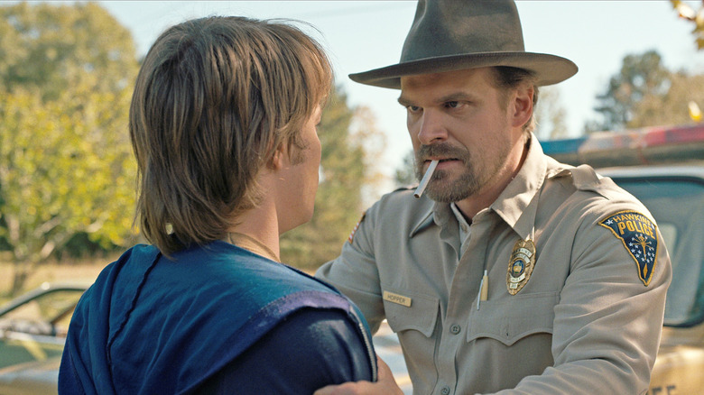 Jim Hopper smoking a cigarette and grabbing Jonathan Byers by the shoulders in Stranger Things