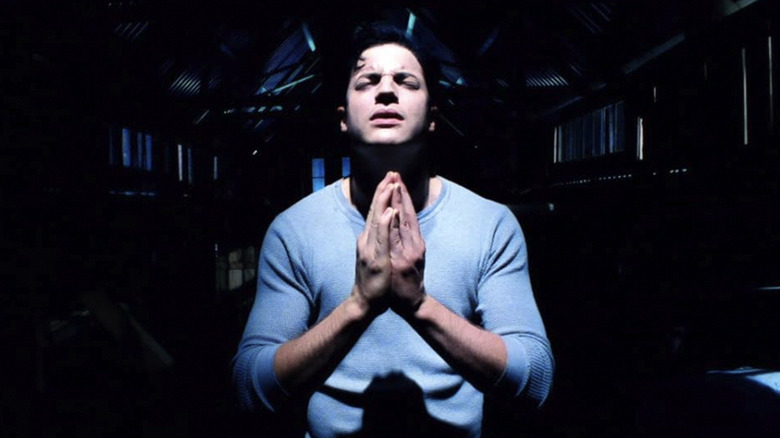 Darkly prays with his eyes closed and his hands together in The Passion of Darkly Noon