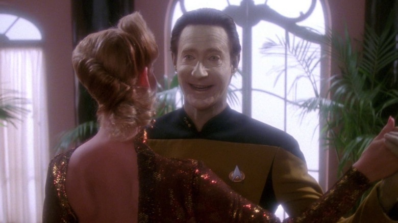 Data, smiling in a fake fashion, dancing in a ballroom with a pretty woman in Star Trek: The Next Generation.