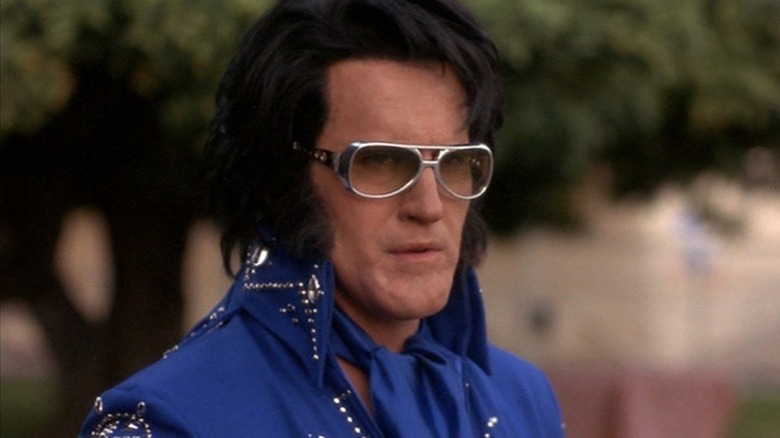 Bruce Campbell as Elvis Presley in his blue suit standing outside in Bubba Ho-Tep