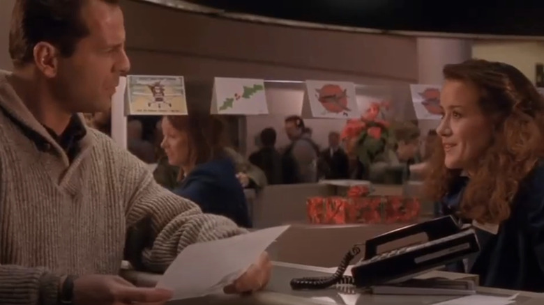 Bruce Willis's John McClane talks to a woman at an airport counter in 
