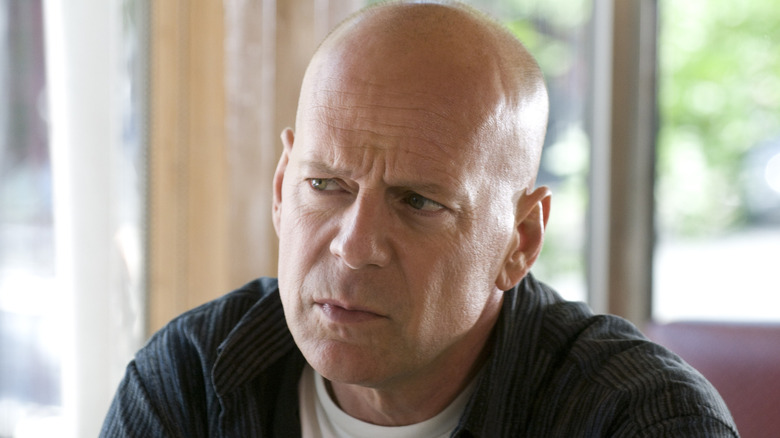 Bruce Willis' Jimmy sitting at a diner table looking sternly in Cop Out